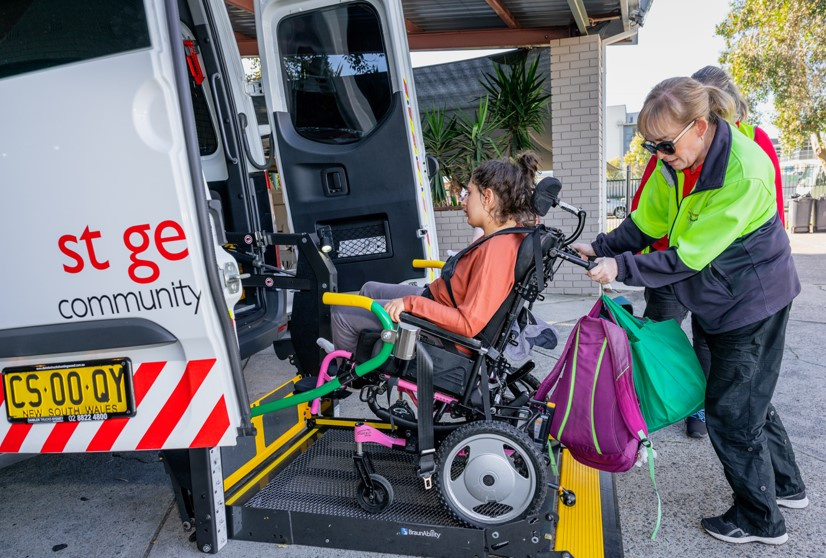 St George Community Support Worker assisting a wheelchair user onto an accessible transport vehicle using the wheelchair lift