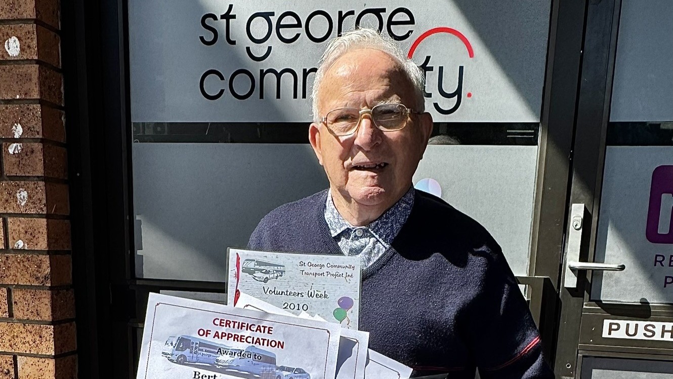 Bert holding volunteer appreciation certificates outside St George Community.
